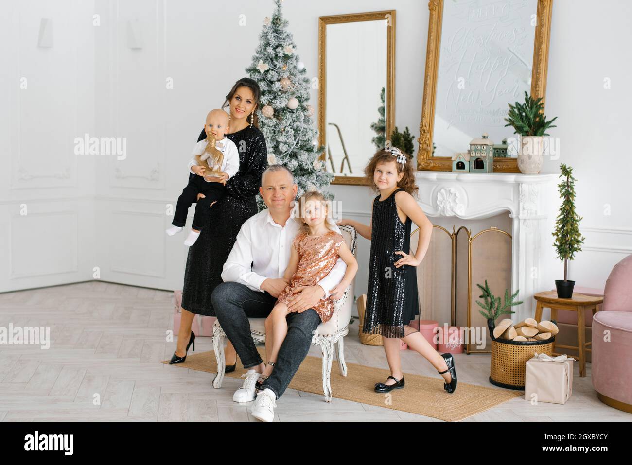 Une belle et belle famille célèbre Noël et le nouvel an dans le salon de leur maison près de l'arbre de Noël Banque D'Images