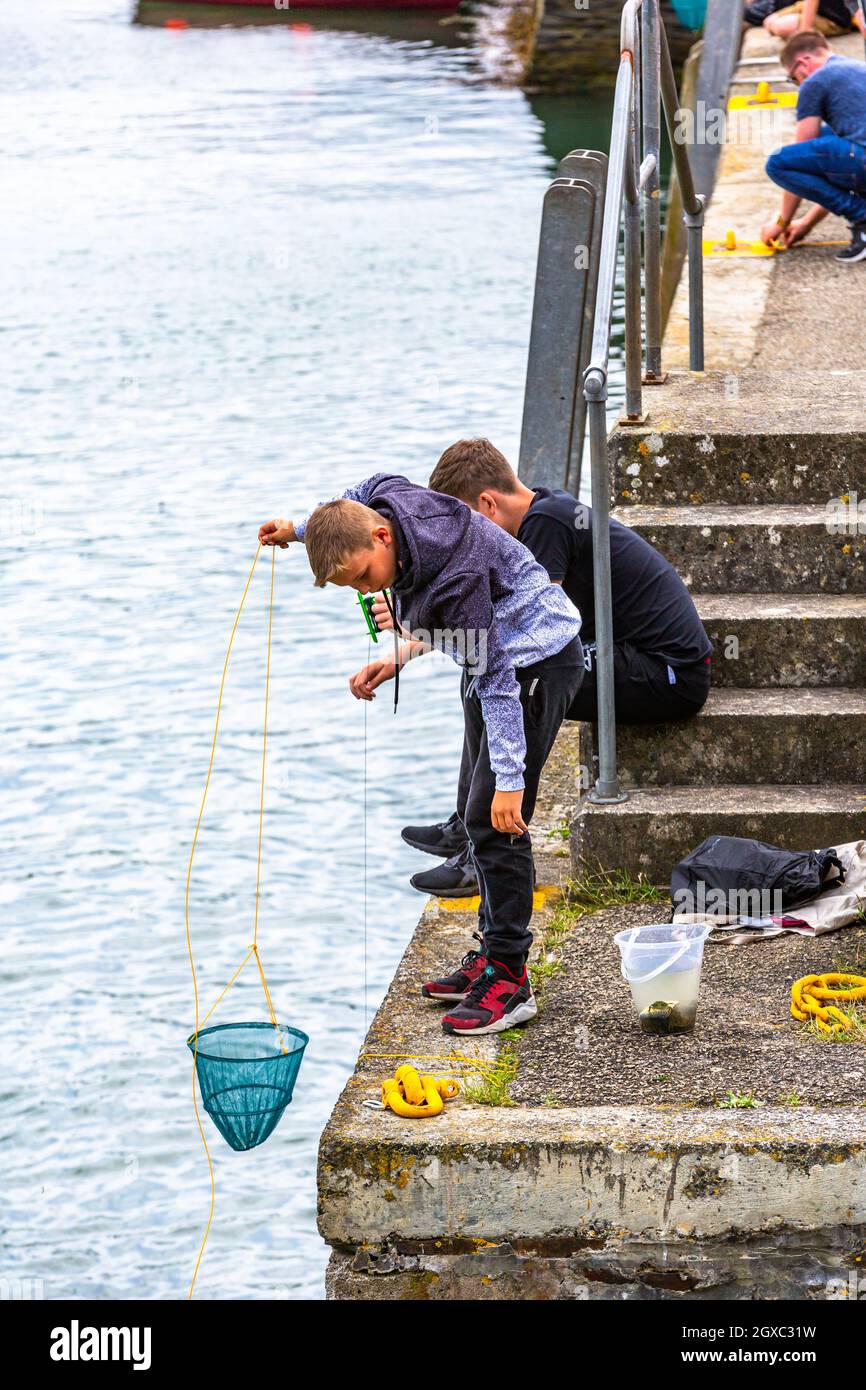 Deux jeunes garçons pêchent du crabe dans un port de Cornwall. Banque D'Images