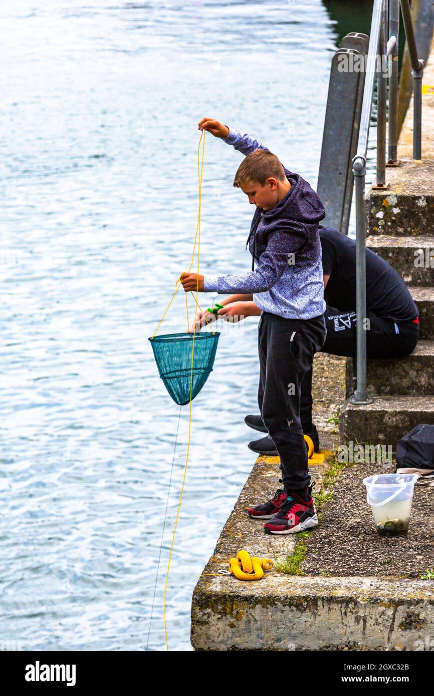 Deux jeunes garçons pêchent du crabe dans un port de Cornwall. Banque D'Images
