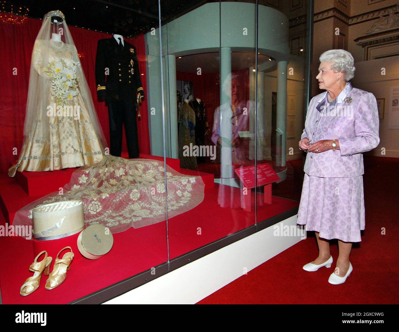 La reine Elizabeth II regarde sa robe de mariée de 1947 et son sentier de  mariée de 13 mètres conçu par Norman Hartnell avec l'uniforme naval porté  par le duc d'Édimbourg, qui