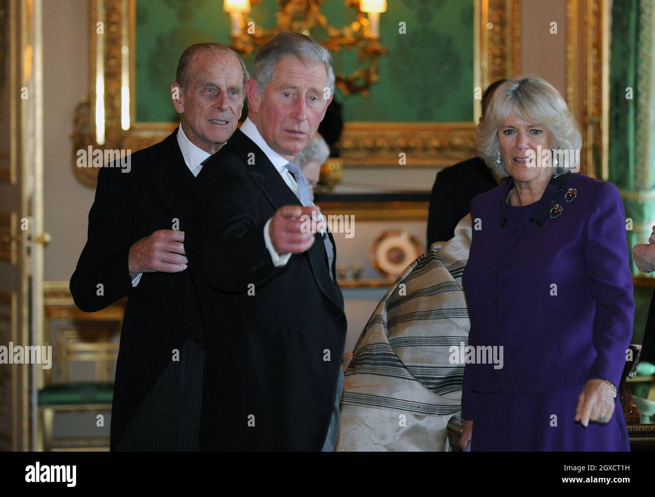 Le Prince Charles, Prince de Galles, Camilla, Duchesse de Cornwall et le Prince Philip, Duc d'Édimbourg, pointent vers des objets lorsqu'ils voient une exposition dans la salle de dessin blanc du château de Windsor au début d'une visite d'État par le Président de l'Inde, Pratibha Patil, le 27 octobre 2009. Banque D'Images