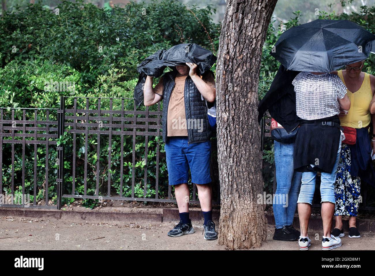 Touristes prenant la couverture de la pluie, Barcelone, Espagne. Banque D'Images