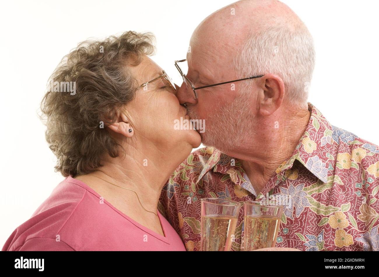 Couple Senior heureux embrasser avec des lunettes de champagne isolées sur  fond blanc Photo Stock - Alamy