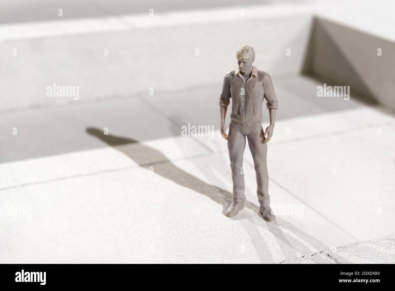 Miniature 3d imprimé monochrome figure d'un homme en vêtement de loisirs debout sur des carreaux jetant une ombre dans la lumière du soleil avec l'espace de copie Banque D'Images
