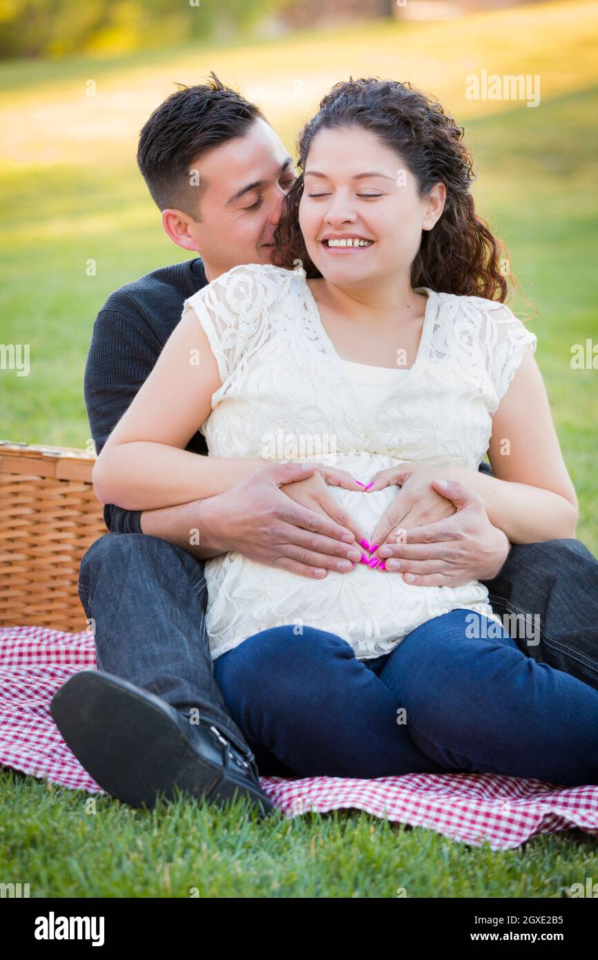 Pregnant Asian Couple forme de coeur avec les mains sur le ventre dans le parc à l'extérieur. Banque D'Images