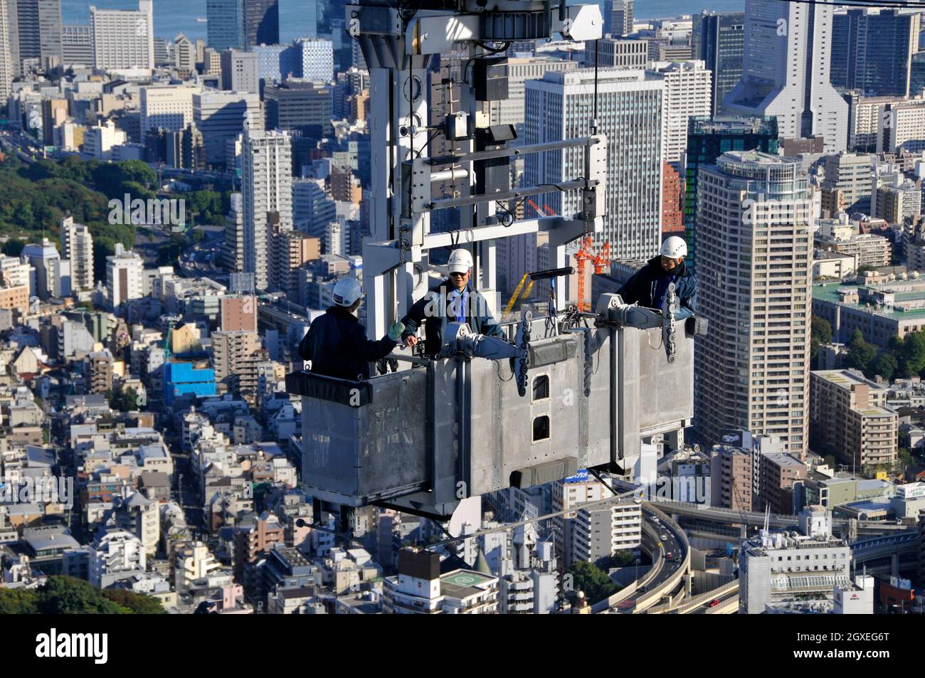 Trois ouvriers de construction sur une grue au sommet de la tour Mori, Roppongi Hills, Tokyo, Japon Banque D'Images