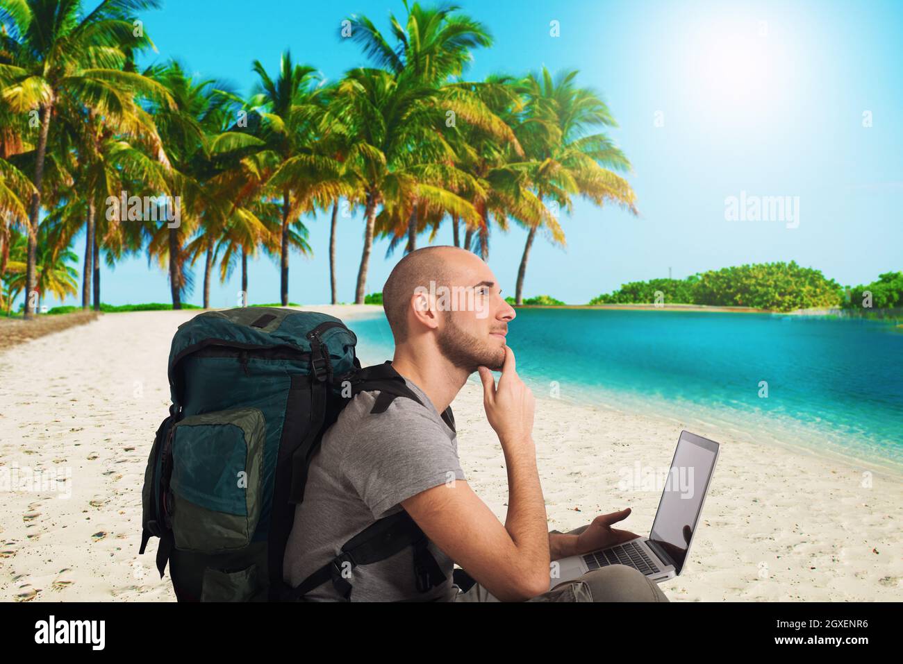 Explorer homme prévoit un nouveau voyage à une plage tropicale avec son ordinateur portable Banque D'Images