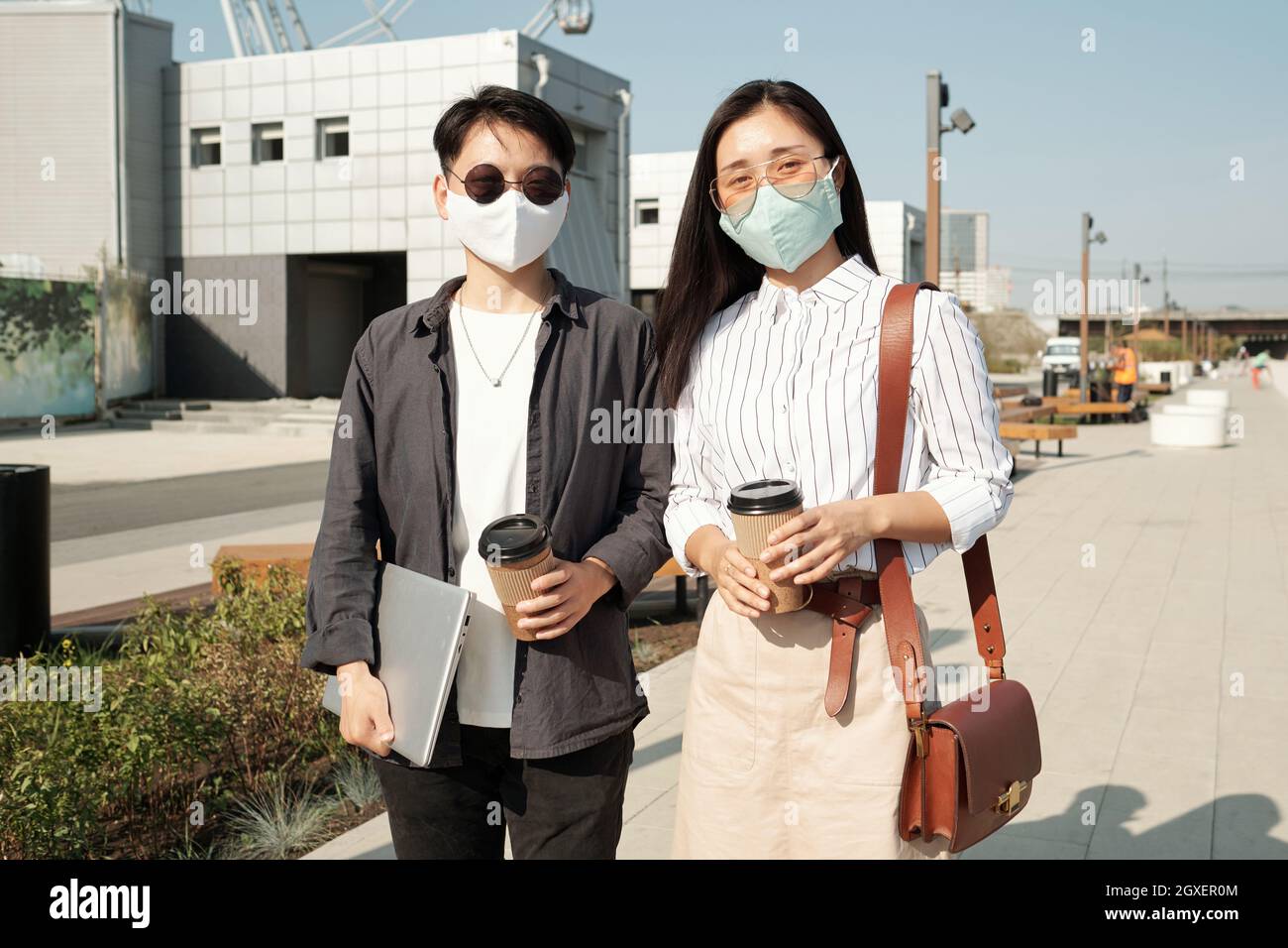 Deux collègues chinois en lunettes et masques de protection se tenant dans la rue Banque D'Images