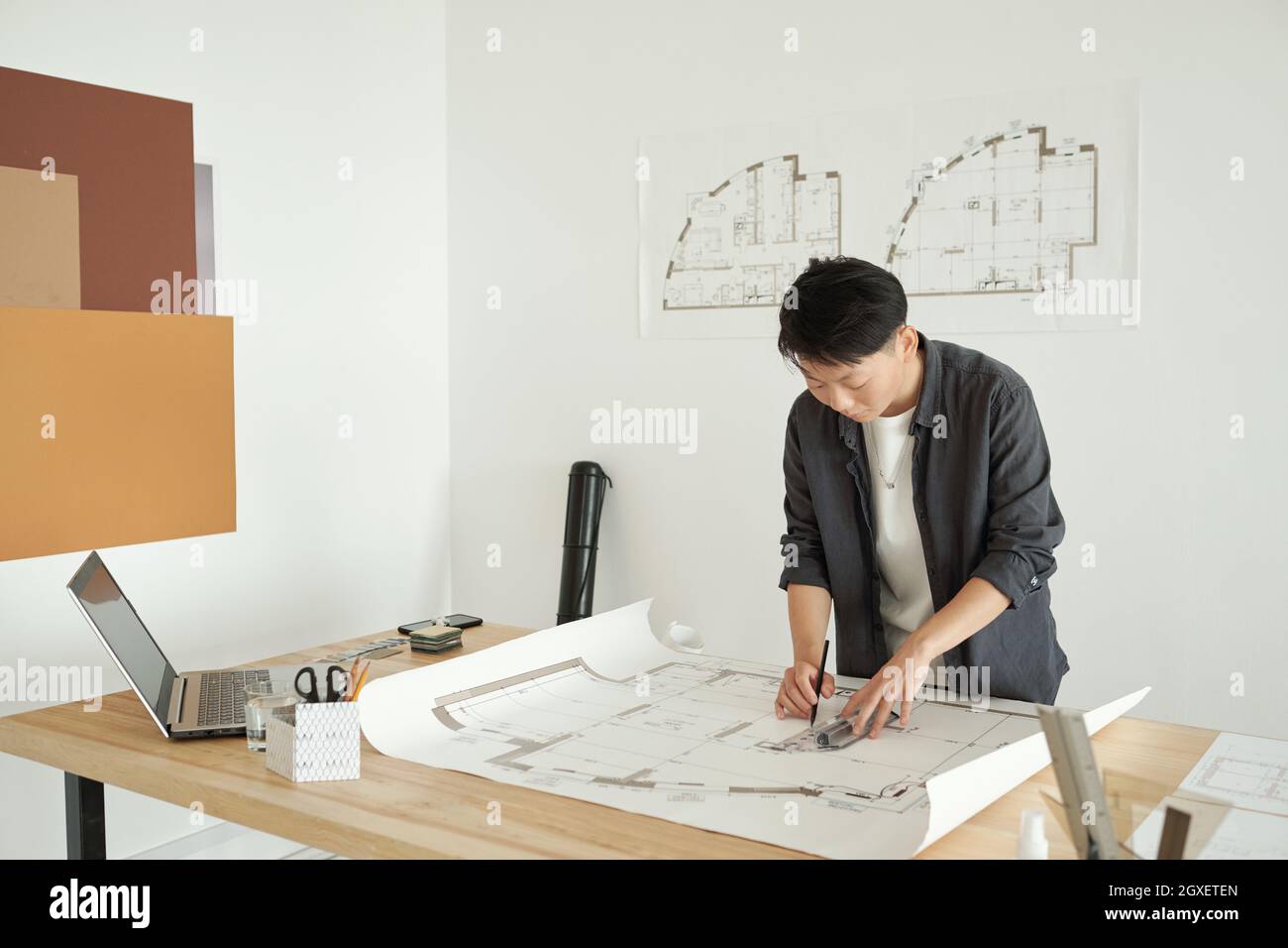 Jeune femme architecte dessinant un croquis de construction tout en se pliant sur le lieu de travail Banque D'Images