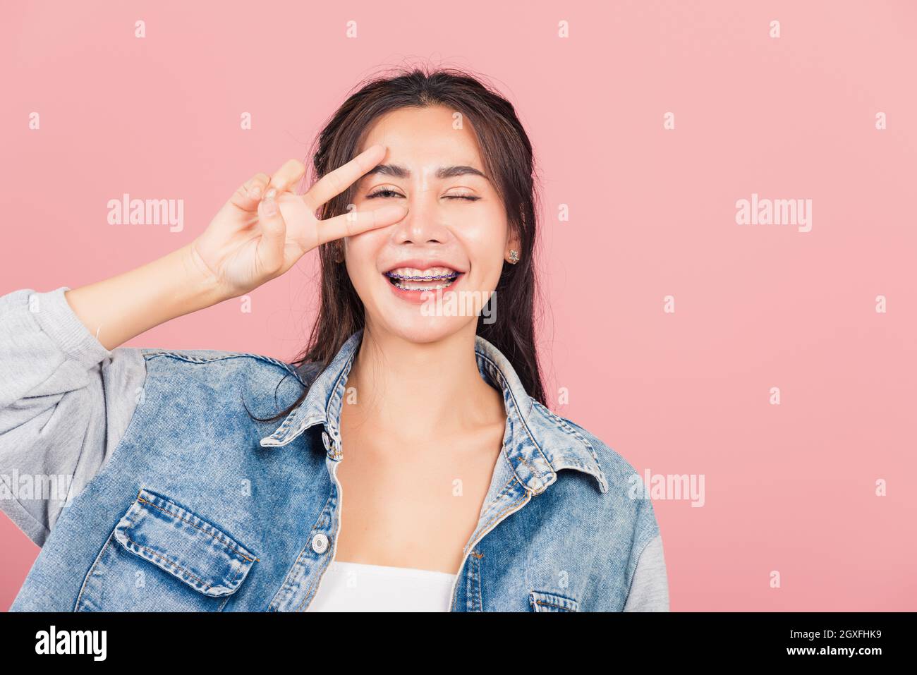Asiatique heureux portrait beau mignon jeune femme porter le sourire denim debout montrant le doigt faisant le symbole de victoire du v-signe près de regarder les yeux à la caméra studi Banque D'Images