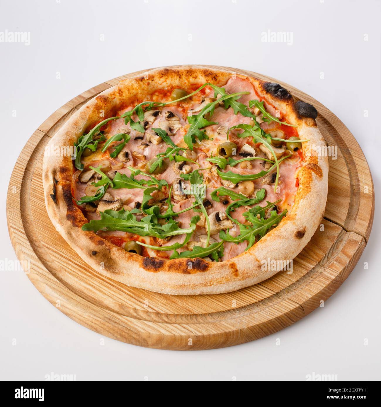 Vue de dessus de pizza chaude sur un stand en bois. Pizza Capricciosa , base de tomate. Jambon tendre, champignons, olives et arugula fraîche à base de deux chés Banque D'Images