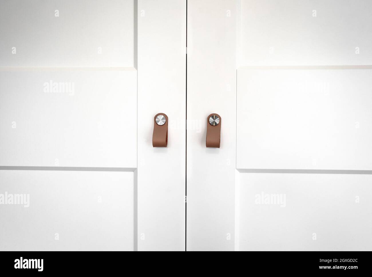 Portes de placard en bois blanc avec poignées en cuir brun rétro bois closeup arrière-plan texture de placard moderne design Banque D'Images