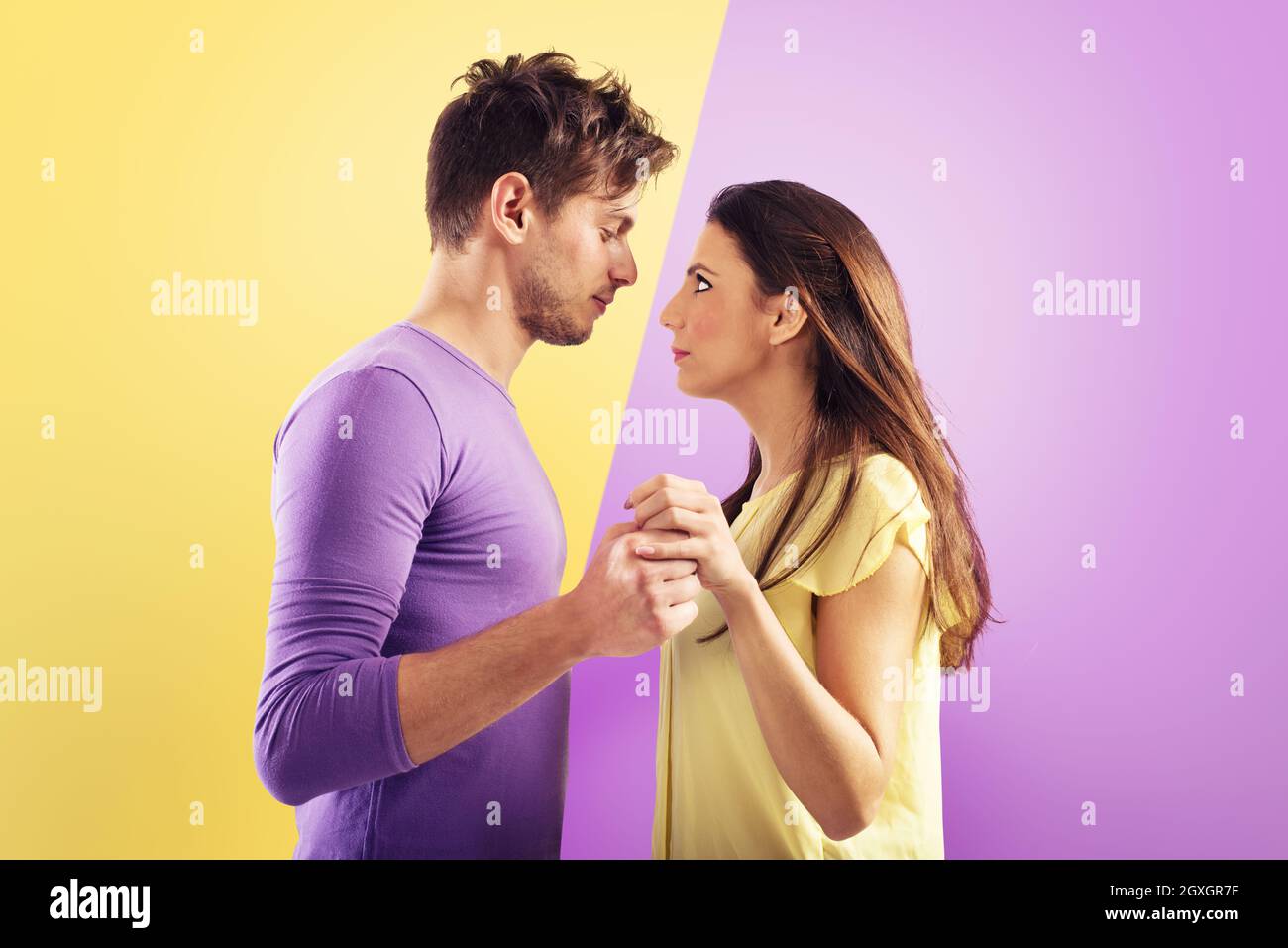 Couple aimant prêt à s'embrasser sur fond violet et jaune Banque D'Images