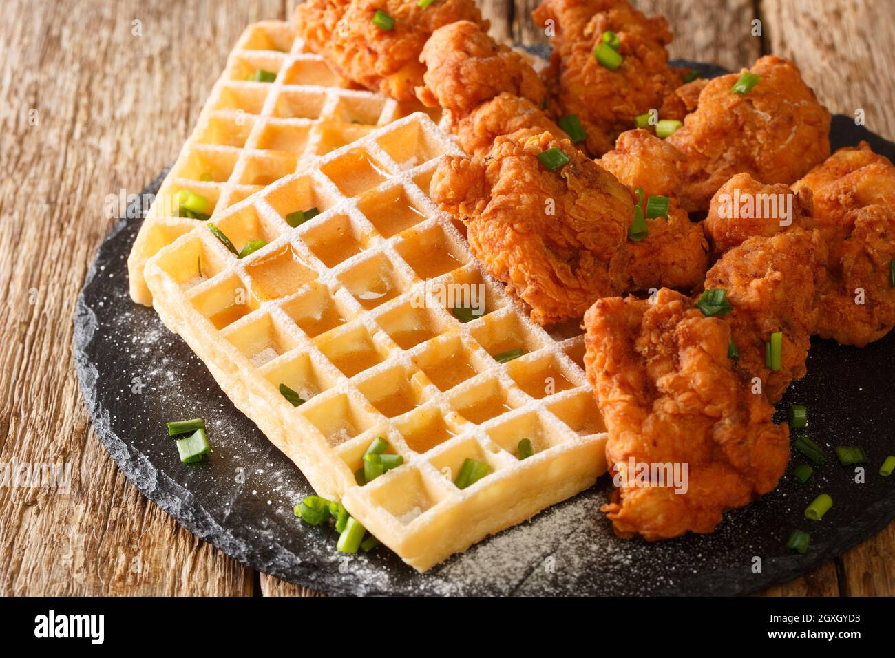 Poulet pané américain et gaufres croustillantes avec sauce au miel sur une assiette en ardoise sur la table. Horizontale Banque D'Images