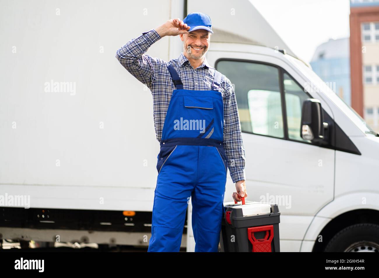 Un technicien de maintenance satisfait dans l'ensemble près d'une fourgonnette ou d'un camion Banque D'Images