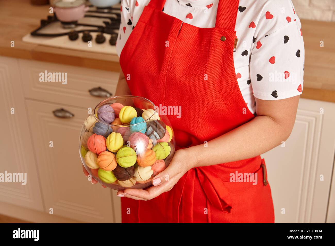 Femme en tablier rouge tenant un bol en verre avec des bonbons Banque D'Images