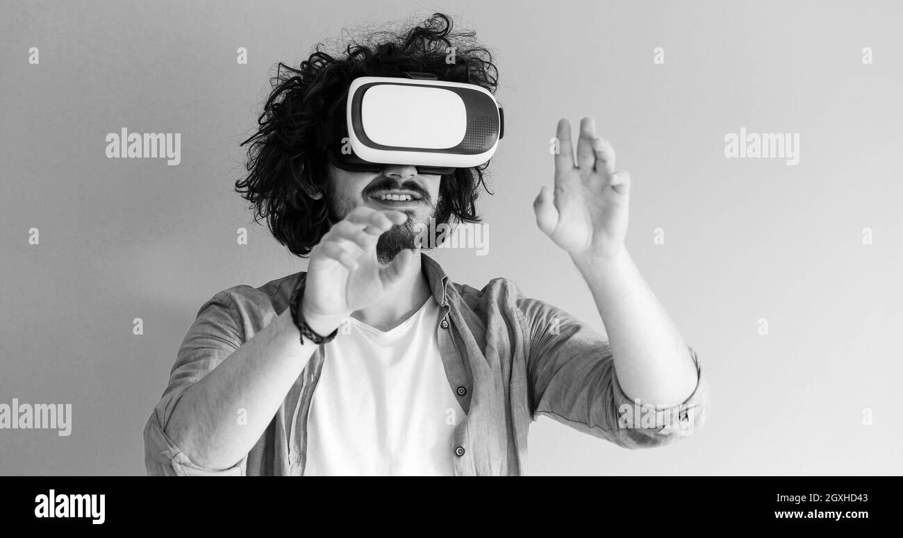 Homme heureux acquérir de l'expérience à l'aide de lunettes casque VR de la réalité virtuelle, isolé sur fond bleu Banque D'Images