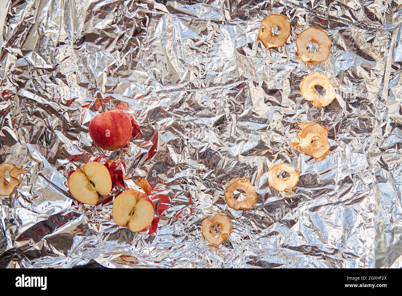 Frites de pommes séchées en tranches et pommes fraîches sur fond de papier d'aluminium - en-cas sains et tendance. Concept de nutrition approprié. Autres encas pour la fête Banque D'Images