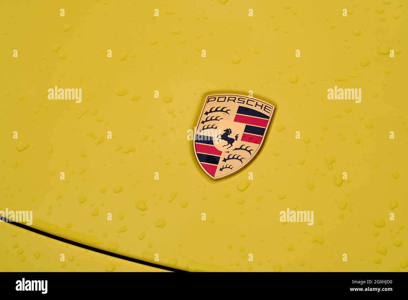 Gros plan du logo Porsche sur une voiture jaune avec gouttes de pluie. Ferdinand Porsche fonde la société en 1931 avec des bureaux principaux dans le centre de Stuttgart. Banque D'Images