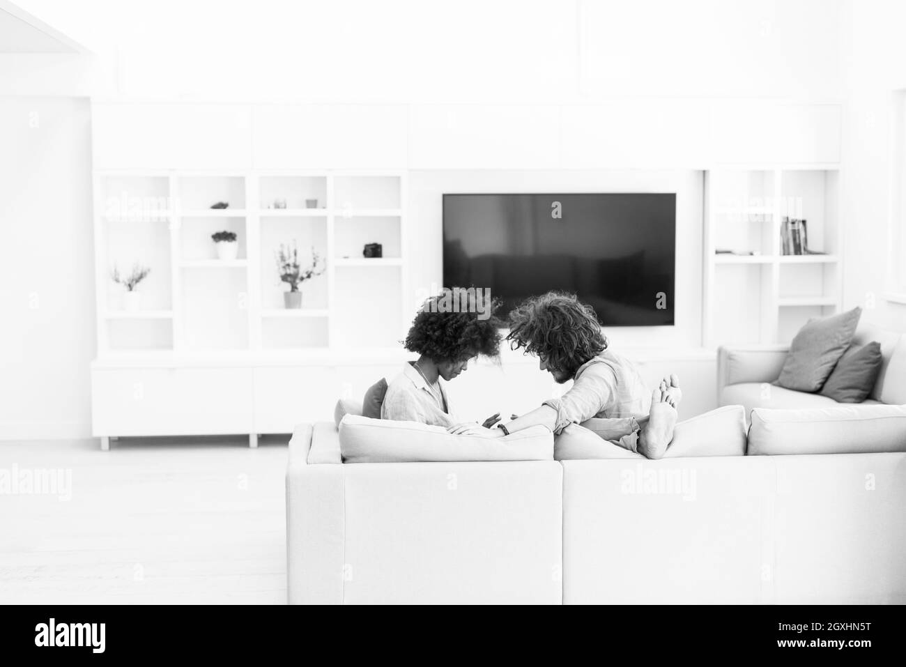 Jeune couple multiethnique assis sur un canapé dans le salon de luxe, à l'aide d'un ordinateur tablette Banque D'Images