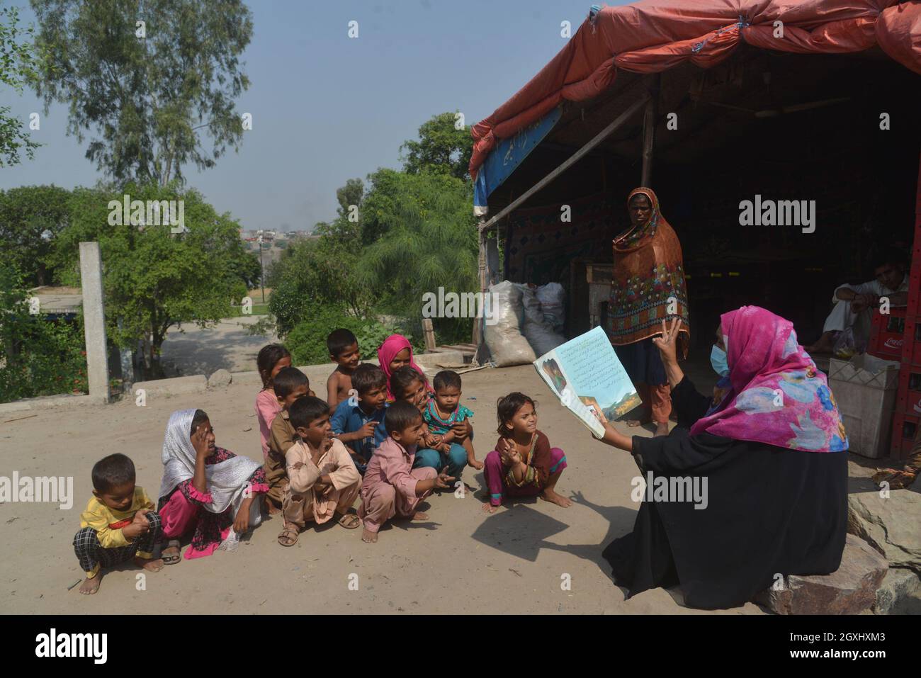 Une volontaire pakistanaise enseigne aux enfants tziganes en plein air dans les maisons d'hébergement temporaire des tziganes le long de la rivière Ravi à la veille de la Journée mondiale des enseignants dans la capitale provinciale à Lahore . Selon l'UNESCO, la Journée mondiale des enseignants représente un élément important de la prise de conscience, de la compréhension et de l'appréciation de la contribution vitale que les enseignants apportent à l'éducation et au développement. La Journée mondiale des enseignants des Nations Unies (ONU) célèbre le rôle que jouent les enseignants dans la prestation d'une éducation de qualité à tous les niveaux. Cela permet aux enfants et aux adultes de tous âges d'apprendre Banque D'Images