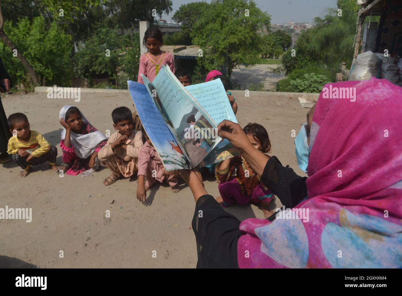 Une volontaire pakistanaise enseigne aux enfants tziganes en plein air dans les maisons d'hébergement temporaire des tziganes le long de la rivière Ravi à la veille de la Journée mondiale des enseignants dans la capitale provinciale à Lahore . Selon l'UNESCO, la Journée mondiale des enseignants représente un élément important de la prise de conscience, de la compréhension et de l'appréciation de la contribution vitale que les enseignants apportent à l'éducation et au développement. La Journée mondiale des enseignants des Nations Unies (ONU) célèbre le rôle que jouent les enseignants dans la prestation d'une éducation de qualité à tous les niveaux. Cela permet aux enfants et aux adultes de tous âges d'apprendre Banque D'Images