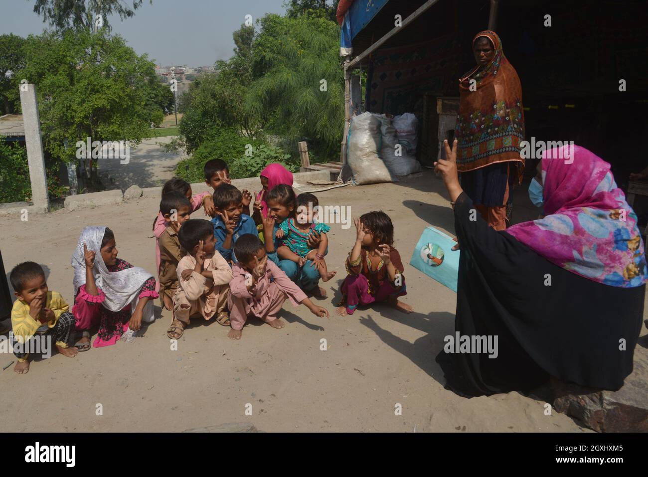 Une volontaire pakistanaise enseigne aux enfants tziganes en plein air dans les maisons d'hébergement temporaire des tziganes le long de la rivière Ravi à la veille de la Journée mondiale des enseignants dans la capitale provinciale à Lahore . Selon l'UNESCO, la Journée mondiale des enseignants représente un élément important de la prise de conscience, de la compréhension et de l'appréciation de la contribution vitale que les enseignants apportent à l'éducation et au développement. La Journée mondiale des enseignants des Nations Unies (ONU) célèbre le rôle que jouent les enseignants dans la prestation d'une éducation de qualité à tous les niveaux. Cela permet aux enfants et aux adultes de tous âges d'apprendre Banque D'Images