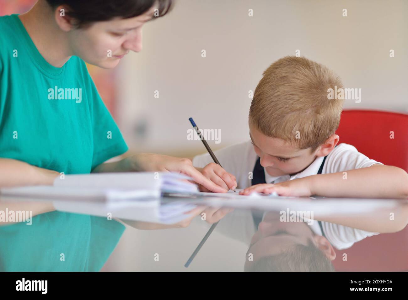 Jeune maman femme Accueil Travailler avec des élèves de l'école primaire à la maison cuisine de garçon Banque D'Images