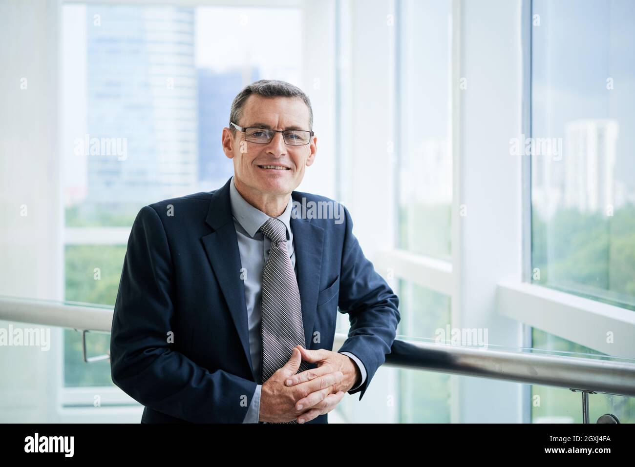 Portrait positif réussi de la société caucasienne cadre en lunettes debout sur le balcon de bureau Banque D'Images