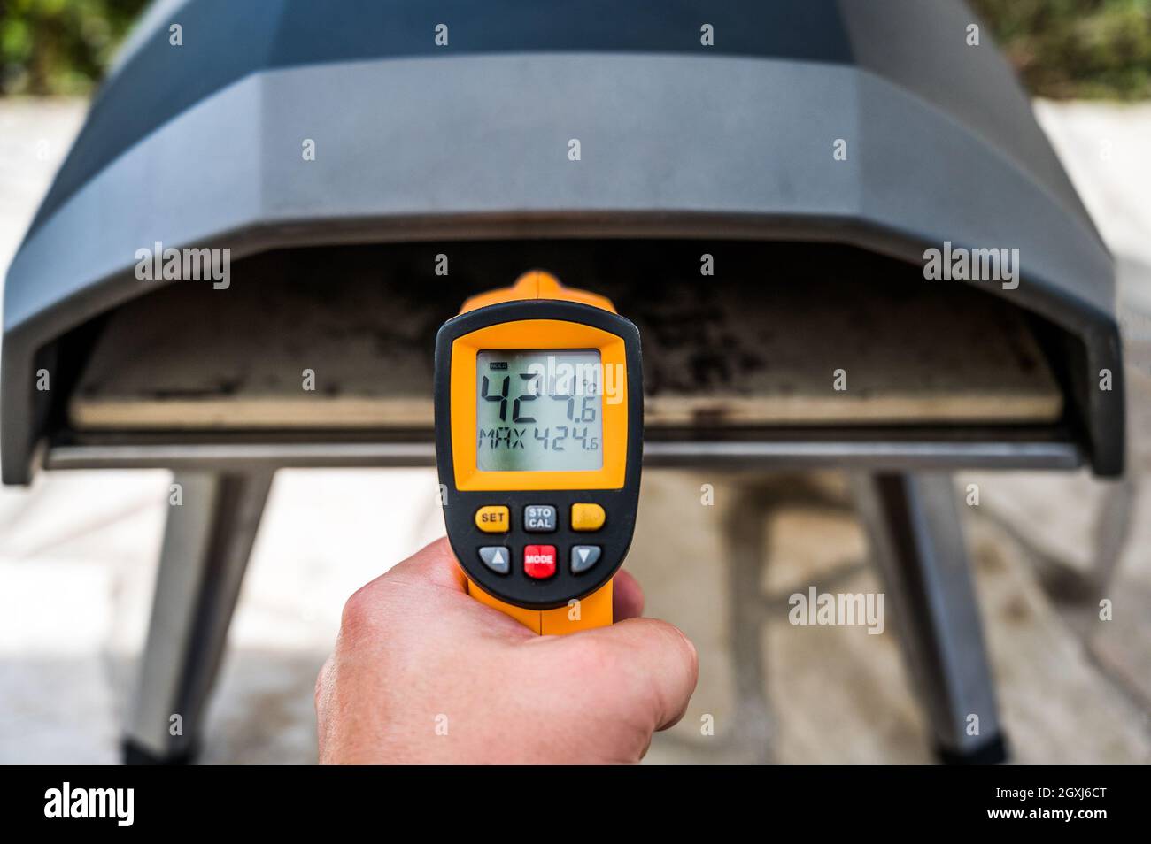 Fabrication de pizza maison dans un four à pizza portable haute température. Vérification de la température de la pierre avec un thermomètre IR spécial. Pizza au gaz spéciale v Banque D'Images Fabrication de pizza maison dans un four à pizza portable haute température. Vérification de la température de la pierre avec un thermomètre IR spécial. Pizza au gaz spéciale v Banque D'Images