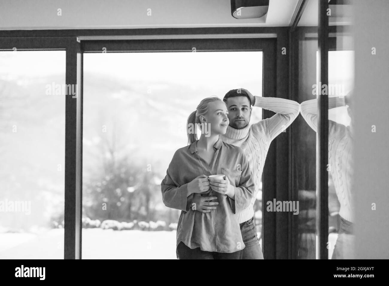Jeune couple romantique bénéficiant d'un plateau par la fenêtre sur l'hiver froid à la maison le soir Banque D'Images