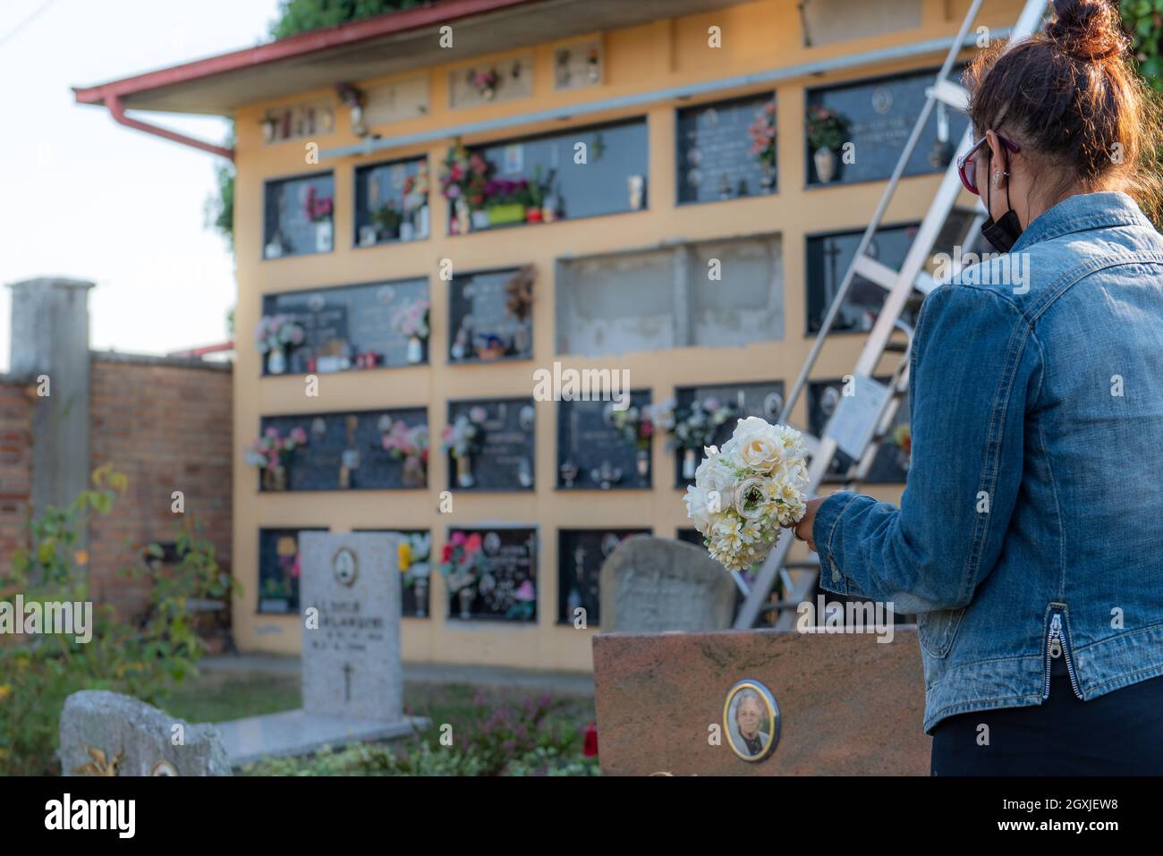 Femme apporte des fleurs au cimetière à l'occasion de la fête de commémoration des morts, ou jour des morts Banque D'Images