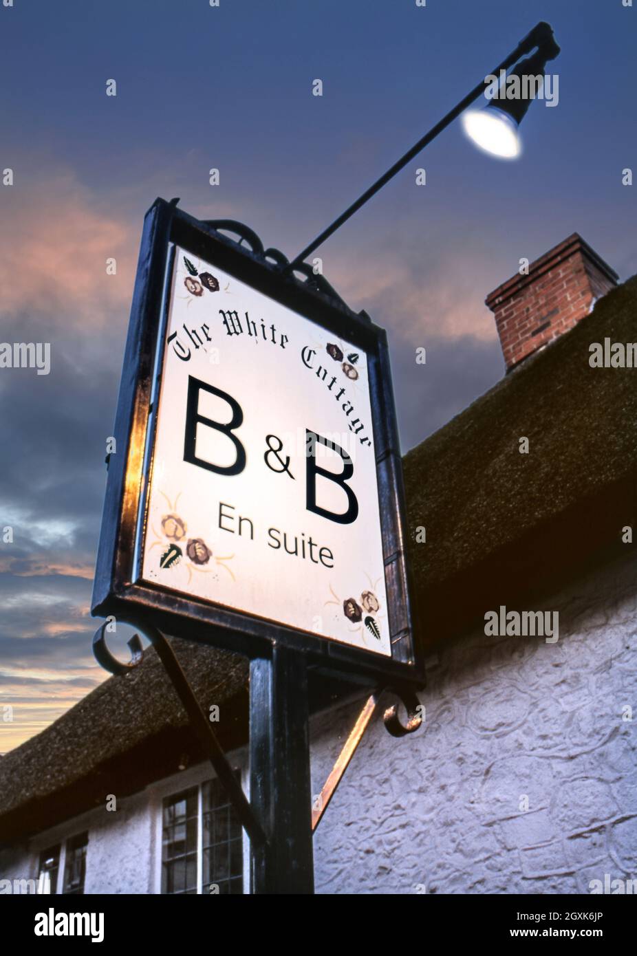 B&B affiche éclairée au coucher du soleil à l'extérieur d'un charmant cottage en chaume typique offrant Bed & Breakfast en suite au White Cottage à Devon, Royaume-Uni anglais britannique Banque D'Images