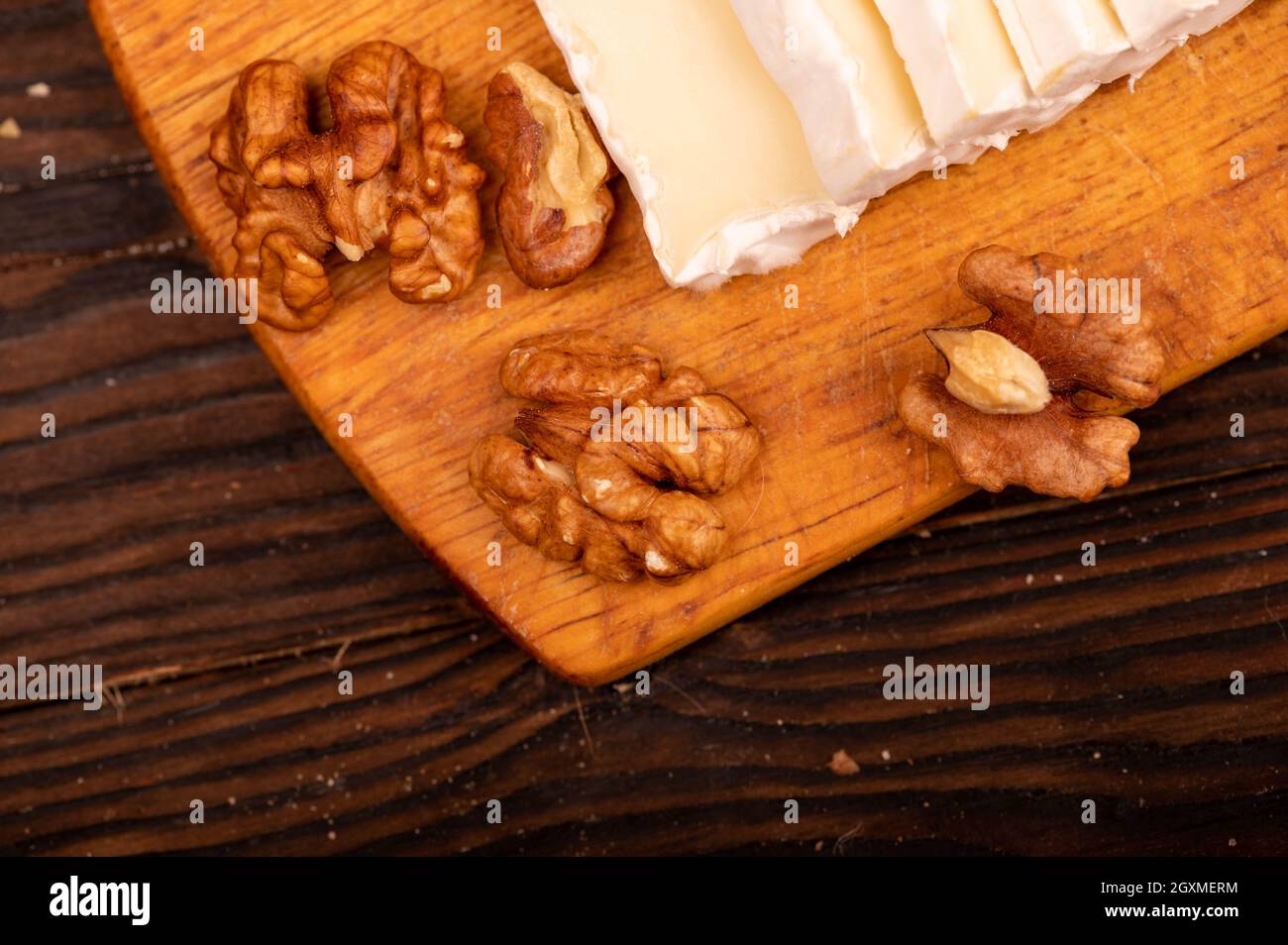 Tranches de camembert et de noix sur une planche à découper en bois, gros plan, mise au point sélective Banque D'Images