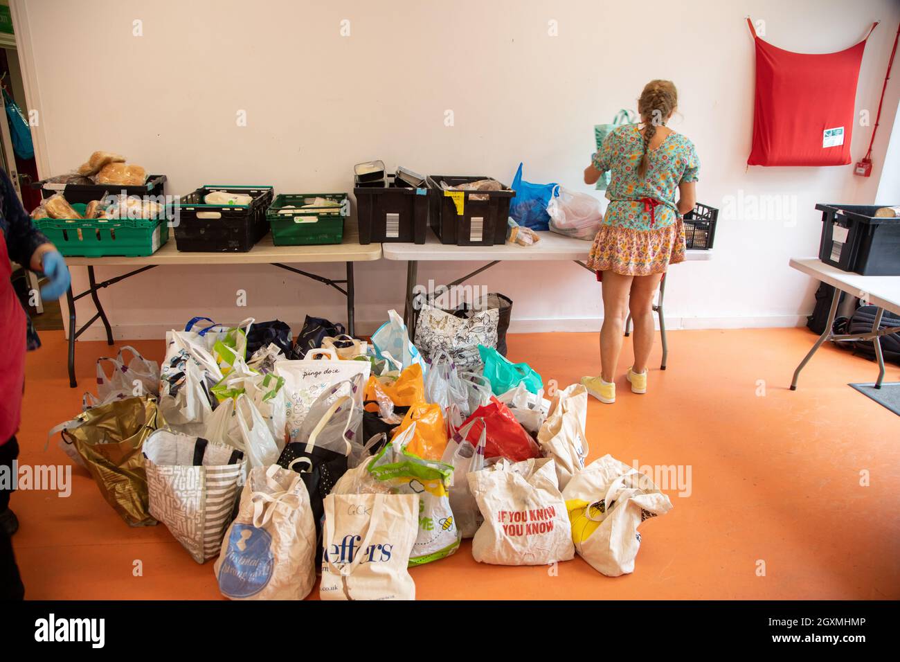 Une femme volontaire dans une banque alimentaire triant des sacs et des caisses de nourriture donnée en vue des distribuer aux membres de la communauté locale dans le besoin. Banque D'Images