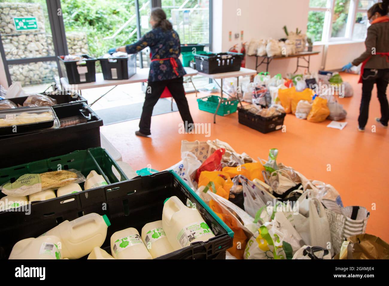 Deux femmes bénévoles dans une banque alimentaire triant des caisses de nourriture en préparation pour la distribution aux membres de la communauté locale dans le besoin. Robot de lait Banque D'Images