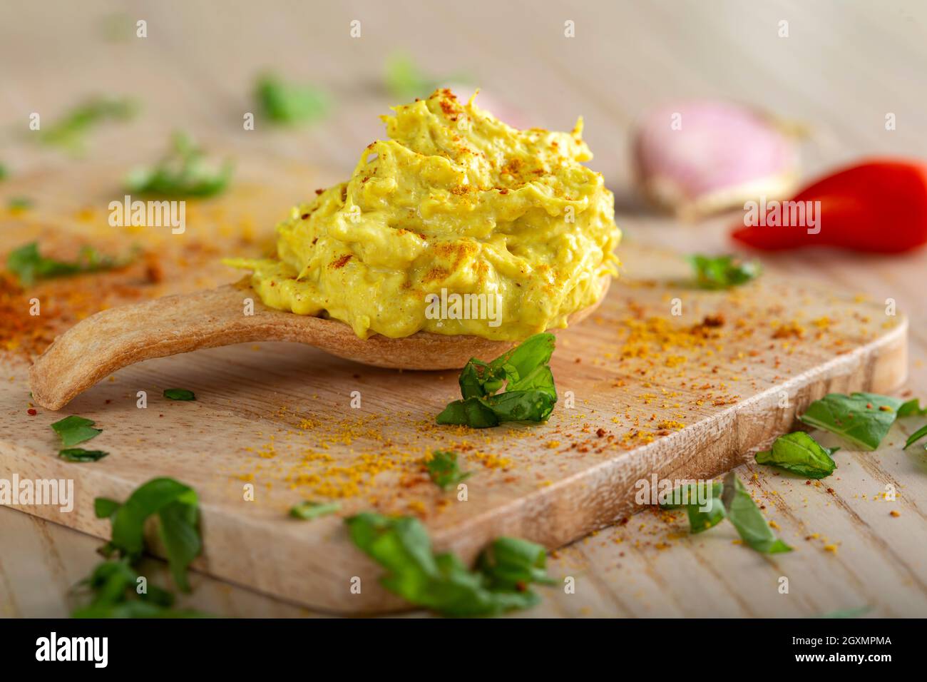 Poulet avec tartiner au curry et paprika moulu dans une cuillère à pâtisserie aux herbes Banque D'Images