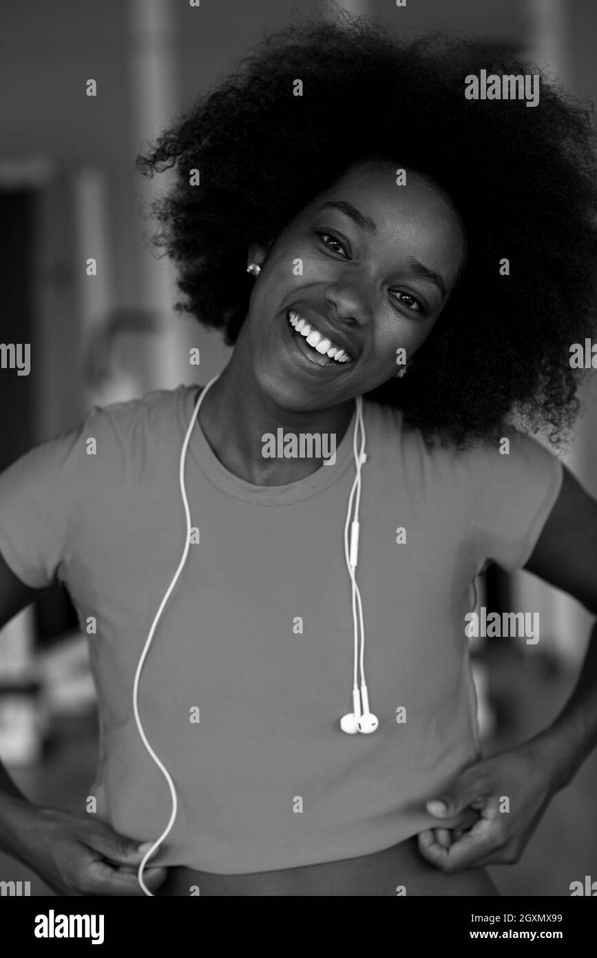 L'afro-américain femme courir sur un tapis roulant dans la salle de sport tout en écoutant la musique sur earphones Banque D'Images