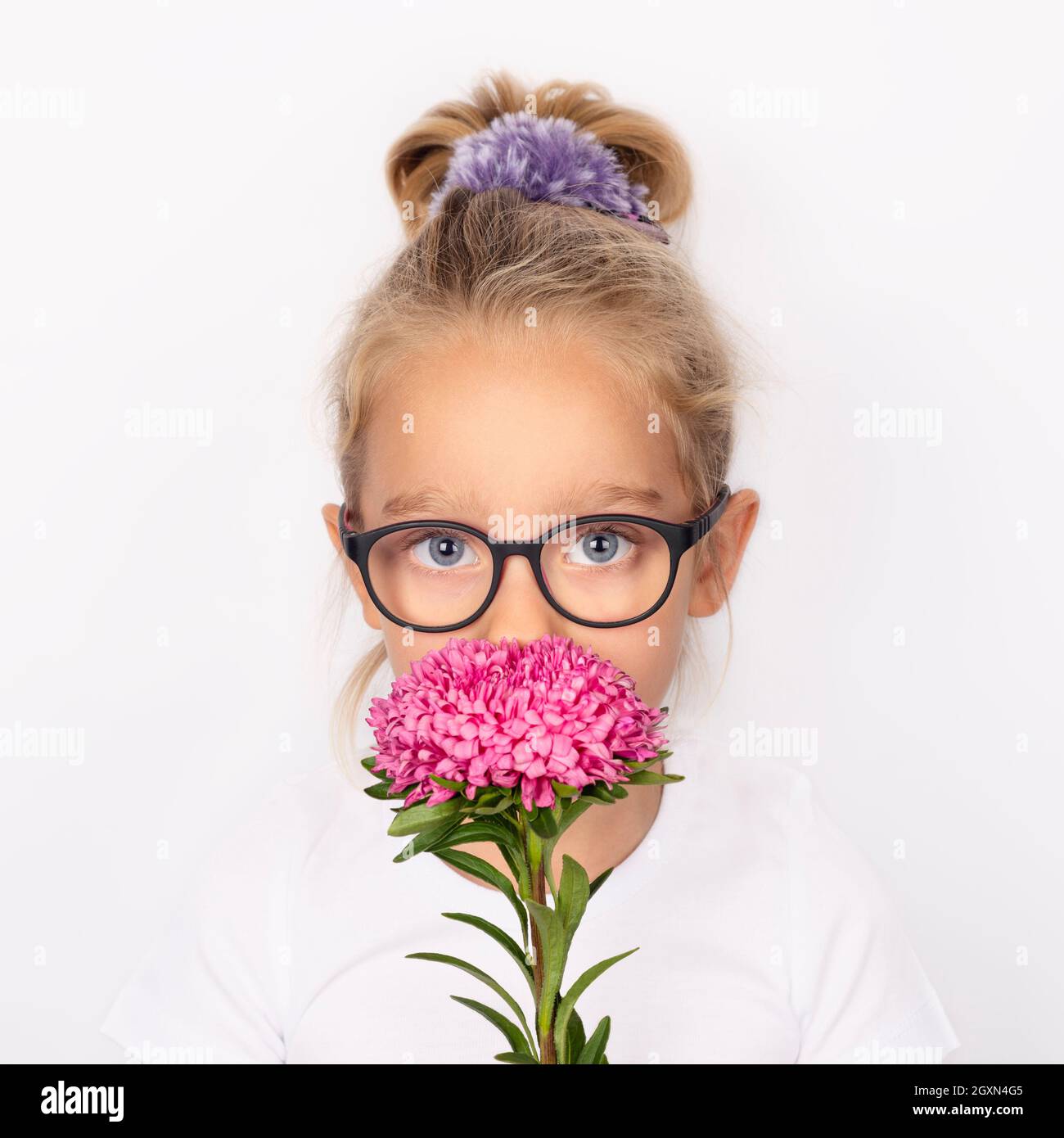 Enfant fille tenant une fleur d'aster rose isolée sur fond blanc. Concept international de la fête des mères Banque D'Images