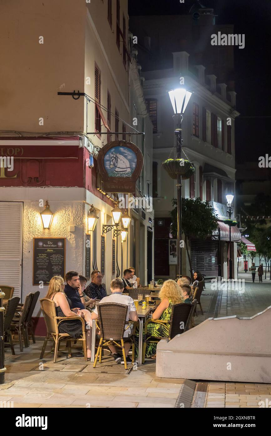 Les gens boivent aux tables de pavement au bar la nuit, Gibraltar Banque D'Images