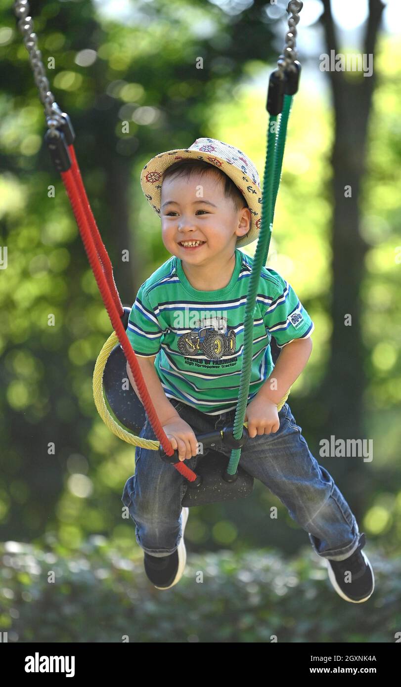 Tout-petit, 2 ans, multiethnique, eurasien, rires,Balançoires sur balançoire pour enfants, Bade-Wurtemberg, Allemagne Banque D'Images