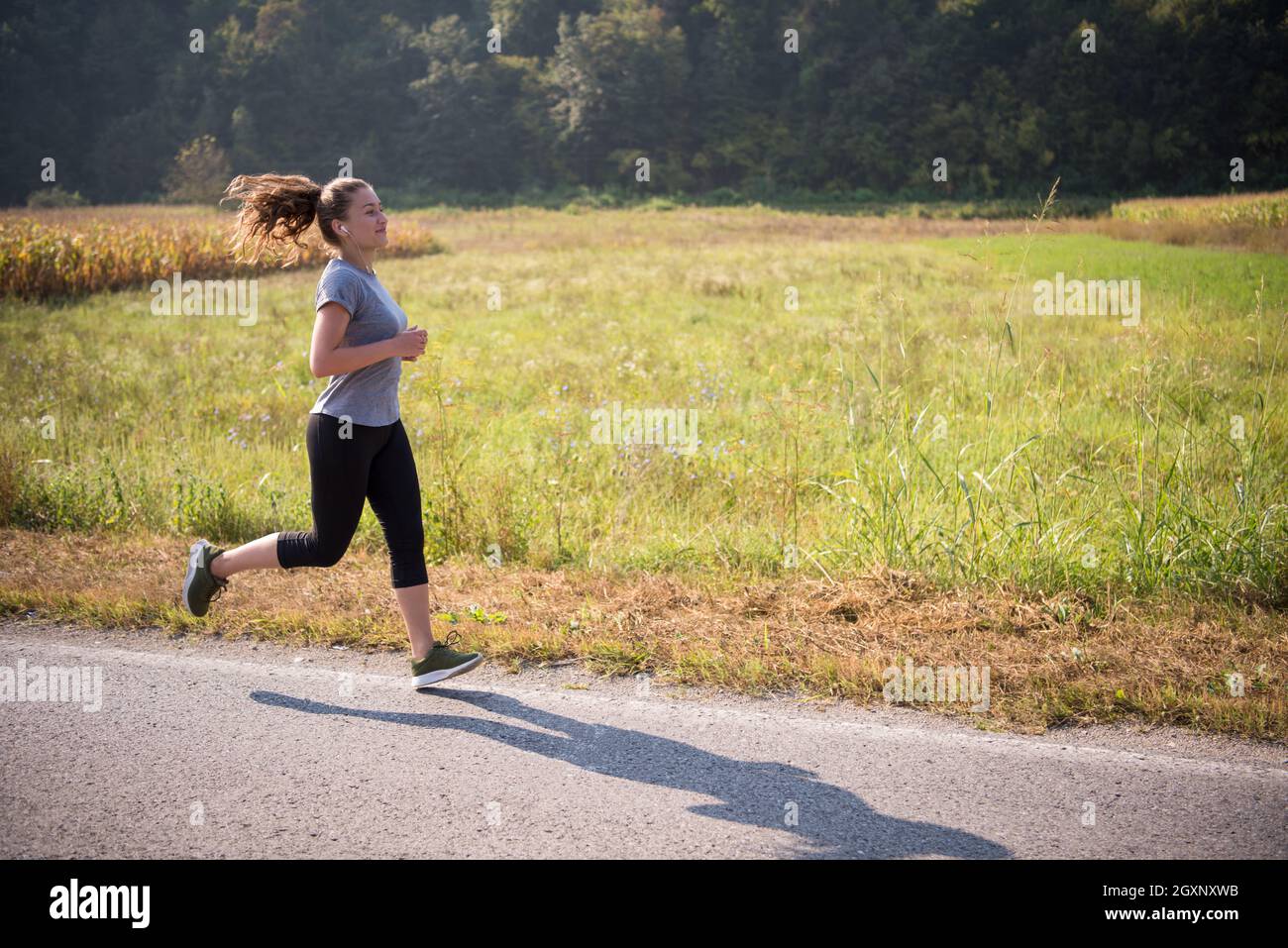 Jeune femme bénéficiant d'une bonne hygiène de vie en faisant du jogging le long d'une route de campagne, l'exercice et fitness concept Banque D'Images