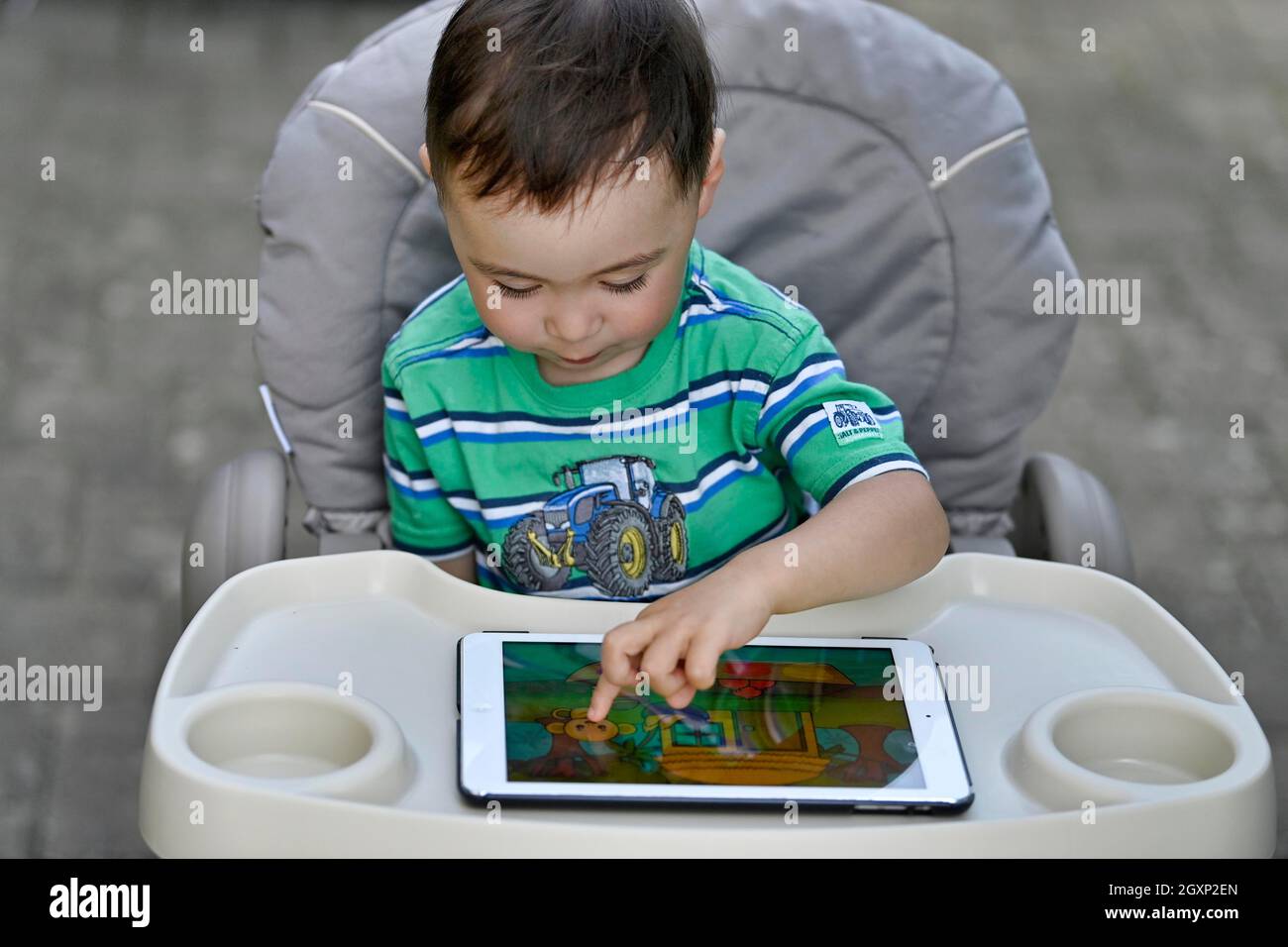 Tout-petit, 2 ans, multiethnique, eurasien, assis en chaise haute et jouant à un jeu éducatif sur tablette, Stuttgart, Baden-Wuerttemberg, Allemagne Banque D'Images