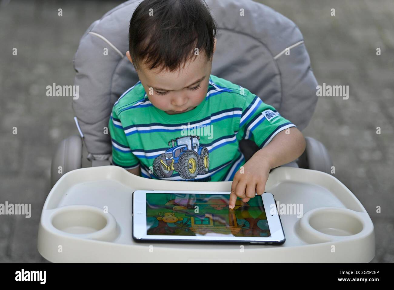Tout-petit, 2 ans, multiethnique, eurasien, assis en chaise haute et jouant à un jeu éducatif sur tablette, Stuttgart, Baden-Wuerttemberg, Allemagne Banque D'Images
