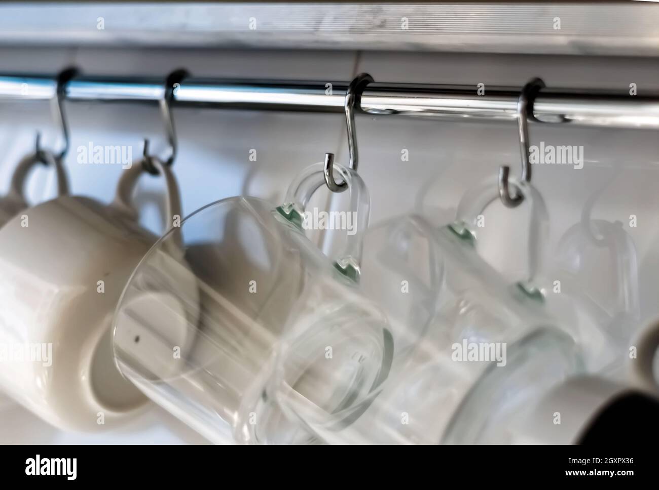 Un ensemble de mugs accrochés sur des crochets dans une cuisine moderne. Objets de tous les jours. Vie domestique. Banque D'Images