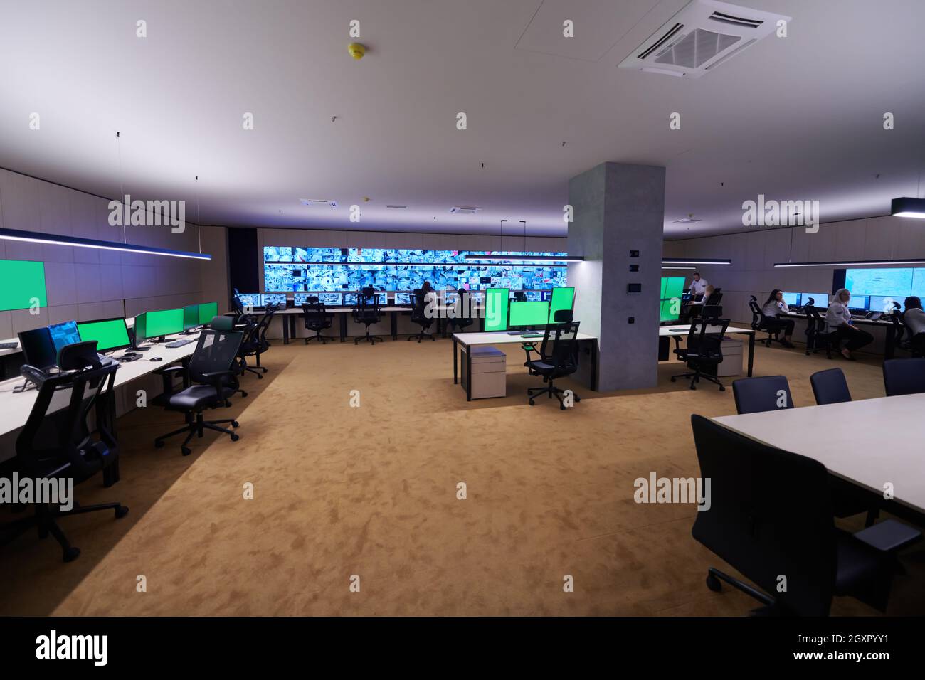 Groupe d'opérateurs de centre de données de sécurité travaillant dans une salle de surveillance CCTV regardant sur plusieurs moniteurs officiers surveillant plusieurs écrans pour Suspi Banque D'Images