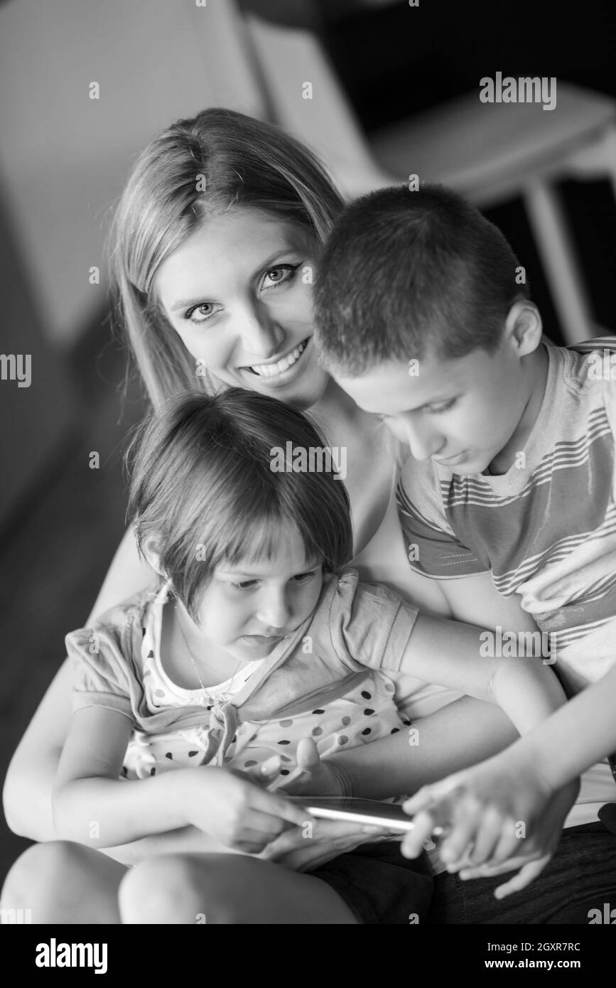 Famille heureuse couchée sur le canapé et à l'aide de Tablet Banque D'Images