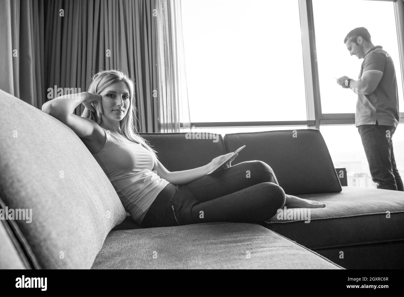 Femme blonde assise sur un canapé en utilisant son Tablet Banque D'Images