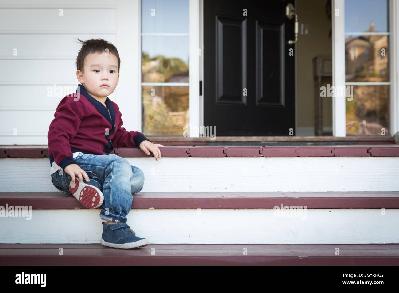 Mélancolie Cute Boy assis sur les marches de la véranda avant. Banque D'Images