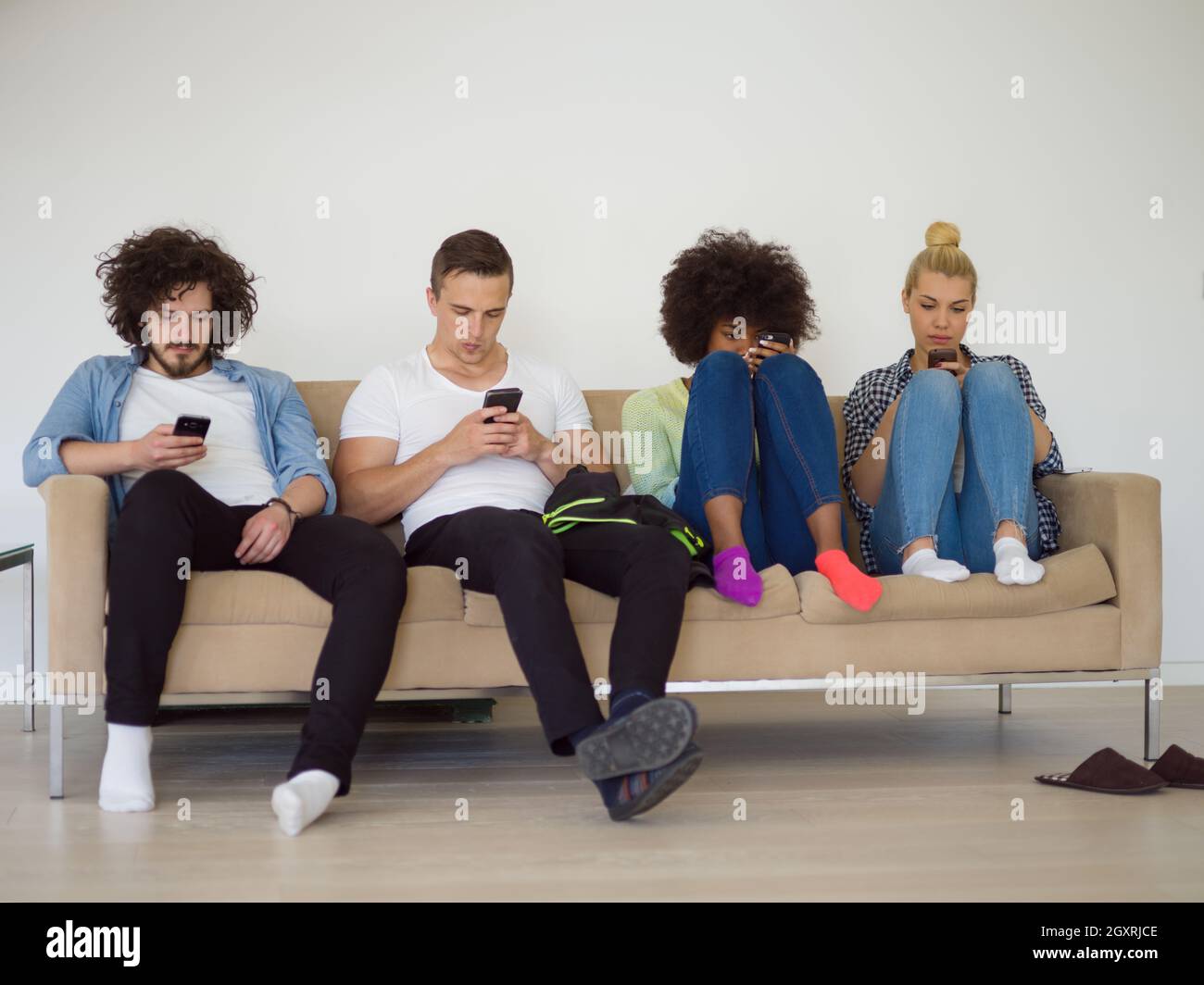 Groupe multiethnique de jeunes gens assis sur un canapé à la maison à regarder,smartphone, smartphone, antisocial en toxicomanie Banque D'Images